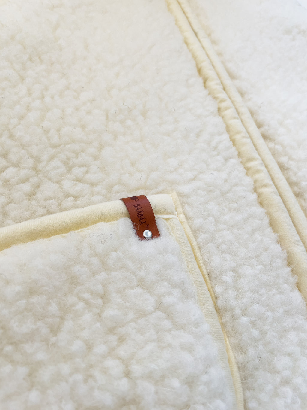 BääBää Fluffi Valkoinen, yksityiskohtainen kuva taskusta – Luonnollinen lampaanvilla huppari, joka tarjoaa mukavuutta ja tyyliä. Hengittävä, lämmin ja mukava päällä.
