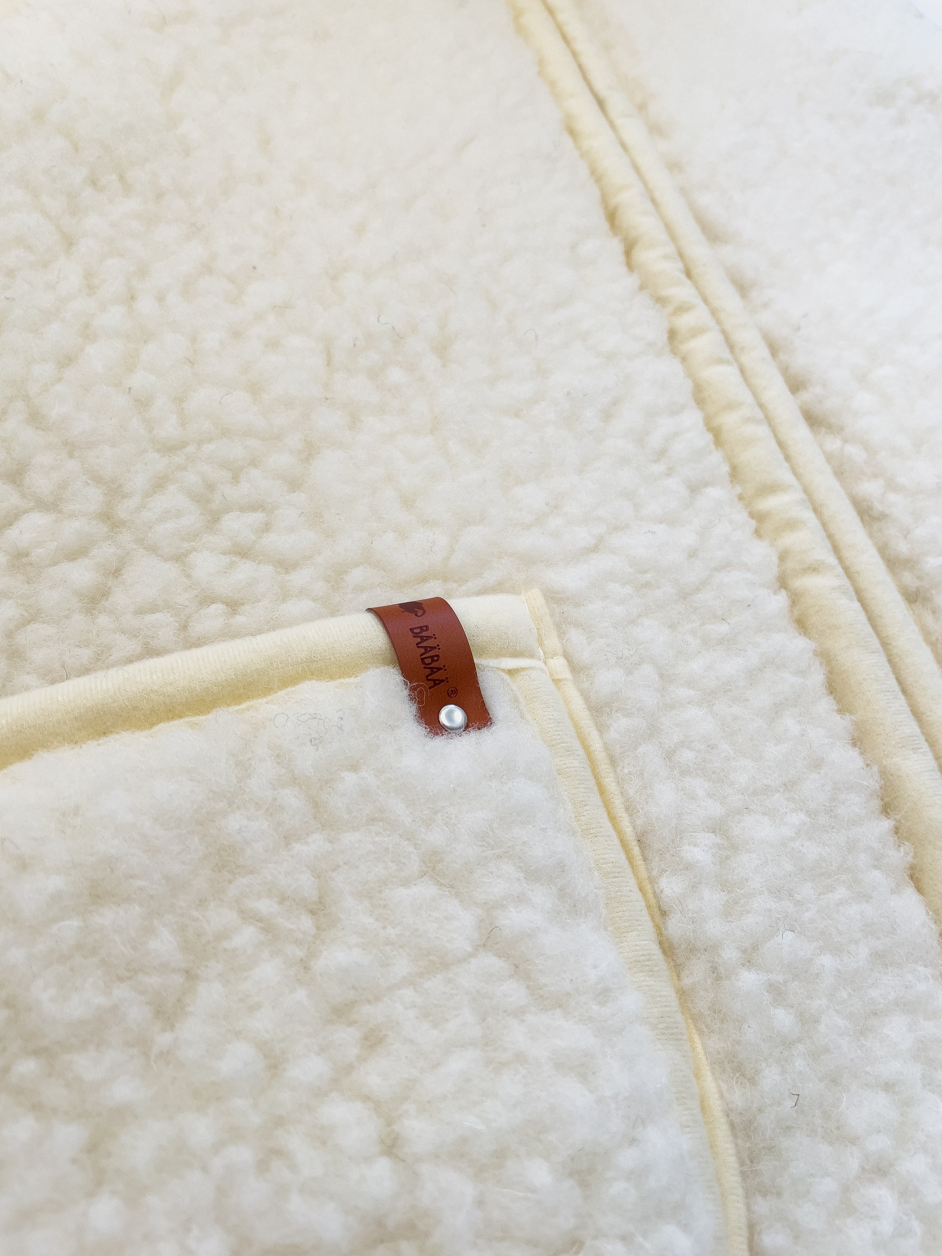 BääBää Fluffi Valkoinen, yksityiskohtainen kuva taskusta – Luonnollinen lampaanvilla huppari, joka tarjoaa mukavuutta ja tyyliä. Hengittävä, lämmin ja mukava päällä.